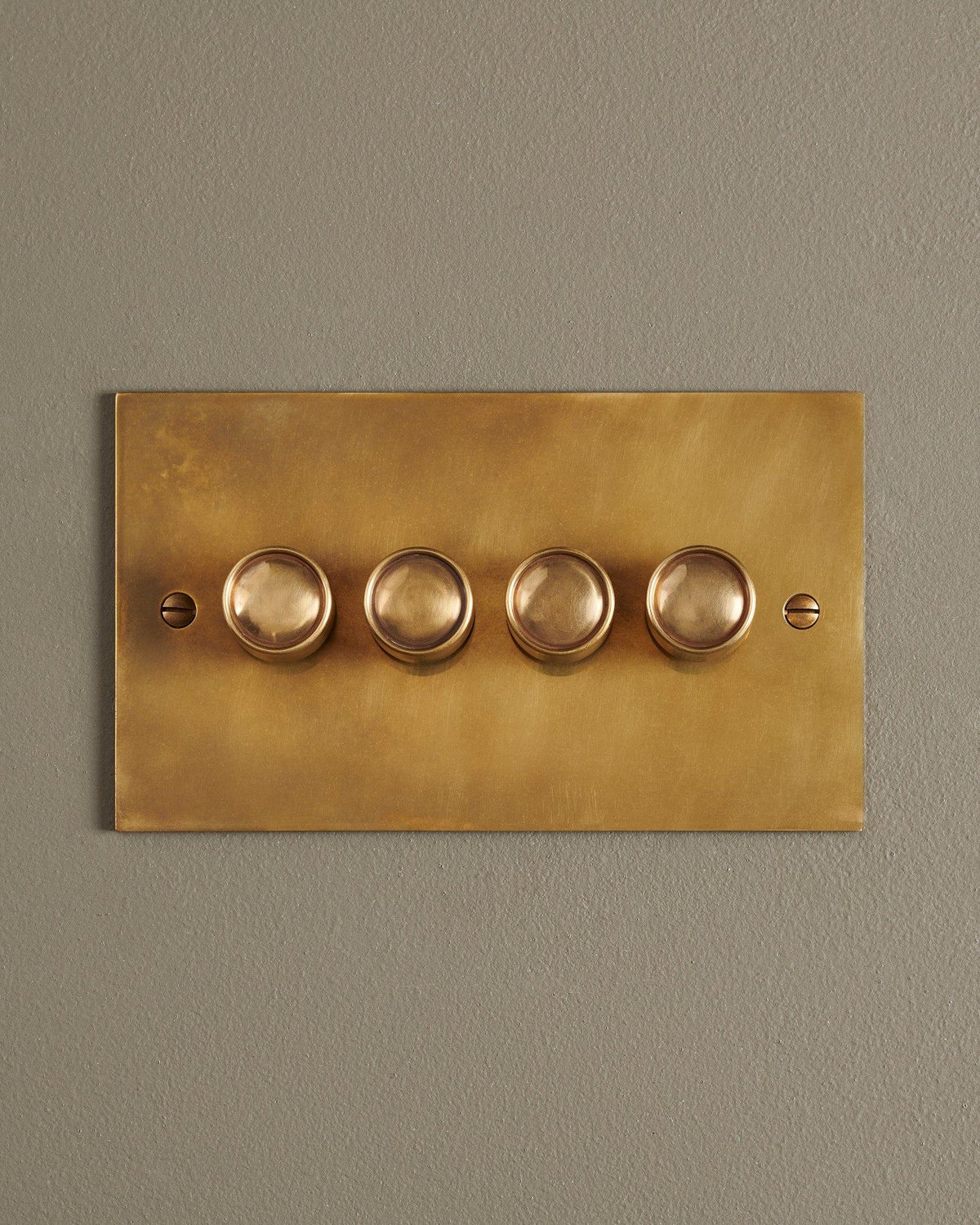 A straight-on view of a 4 gang classic dimmer switch in a warm burnished brass finish. TEST