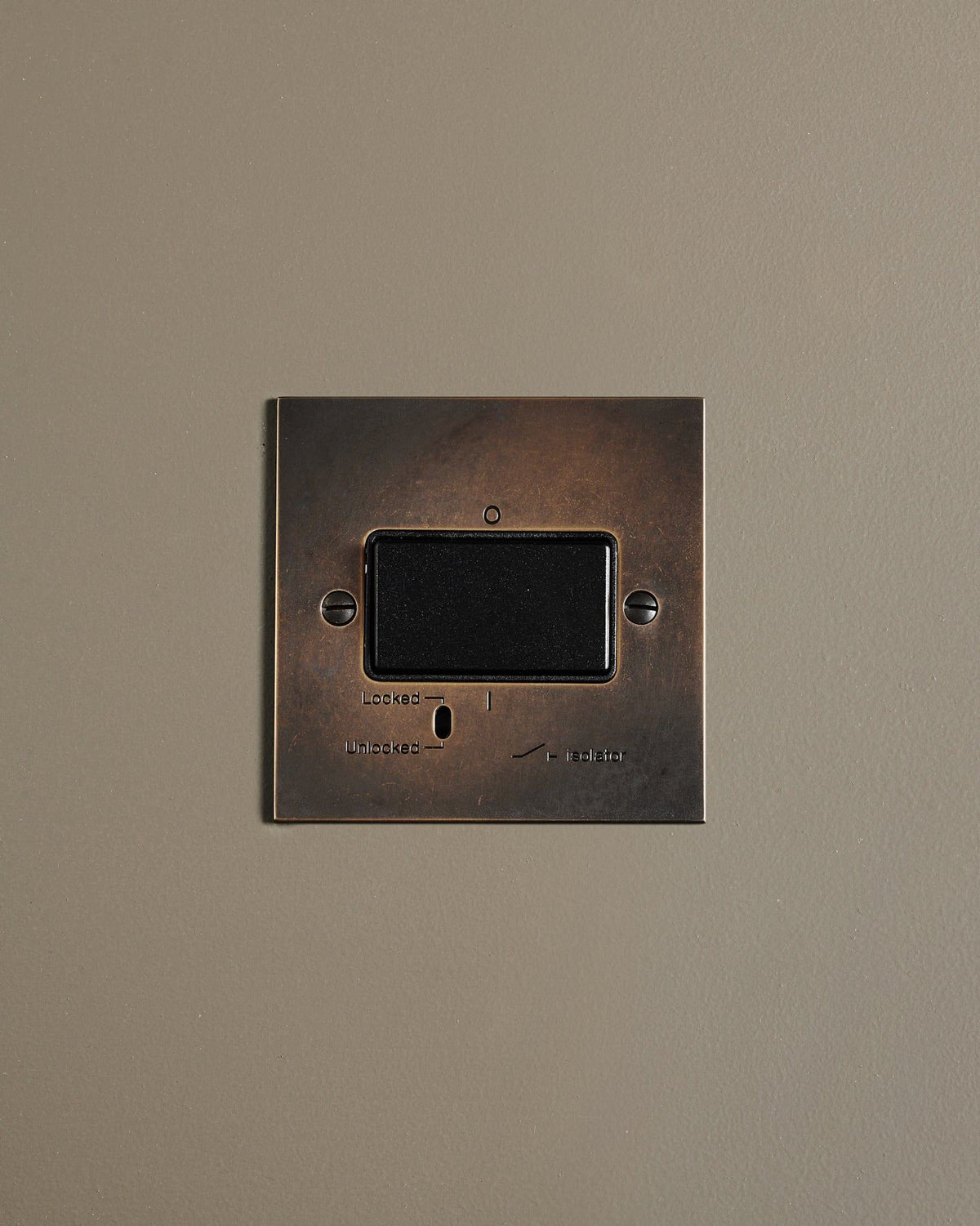 A straight-on view of a classic extractor fan isolator switch a dark oxidised brass finish. TEST
