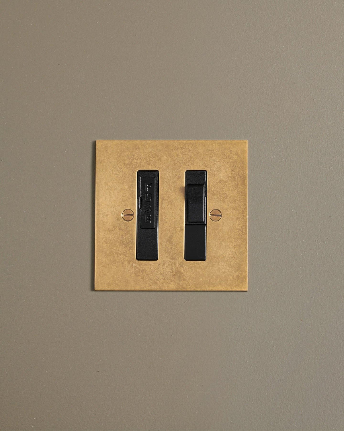 A straight-on view of a classic fused connection switch in a mottled aged brass finish. TEST