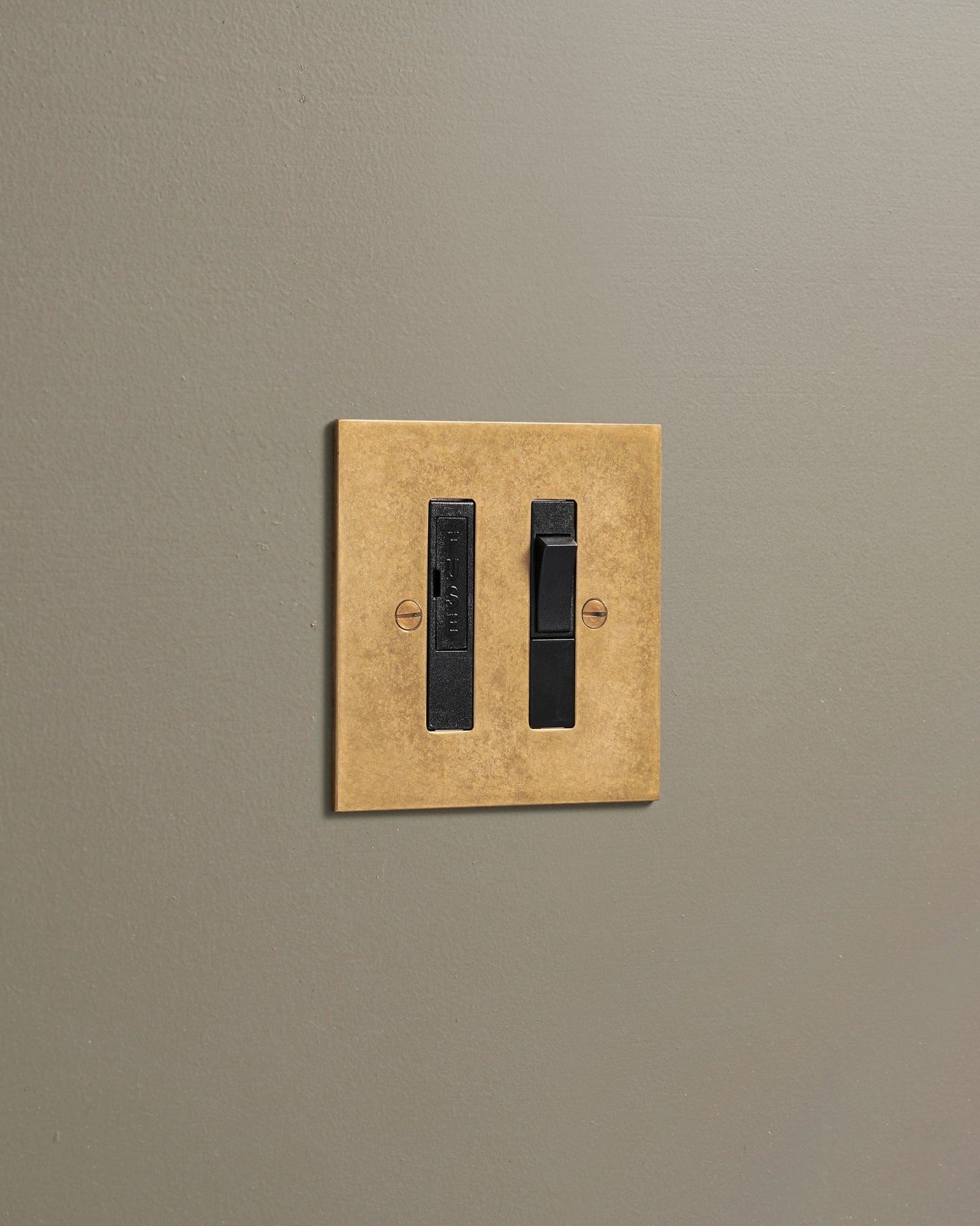 An oblique view of a classic fused connection switch in a mottled aged brass finish.