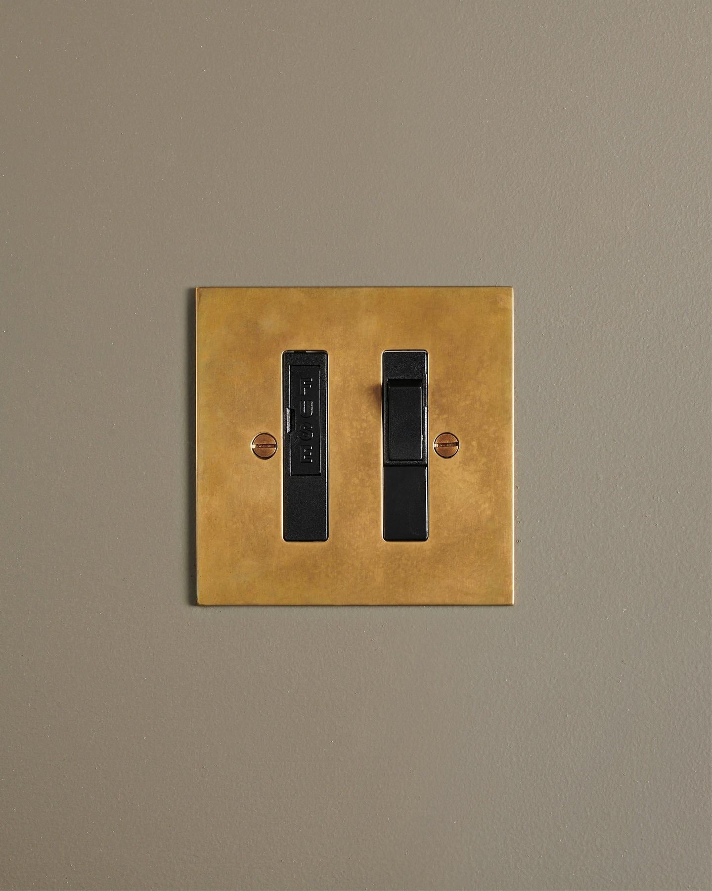 A straight-on view of a classic fused connection switch in a warm burnished brass finish.