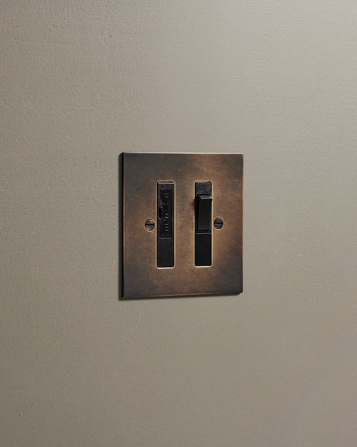 An oblique view of a classic fused connection switch in a dark oxidised brass finish. TEST
