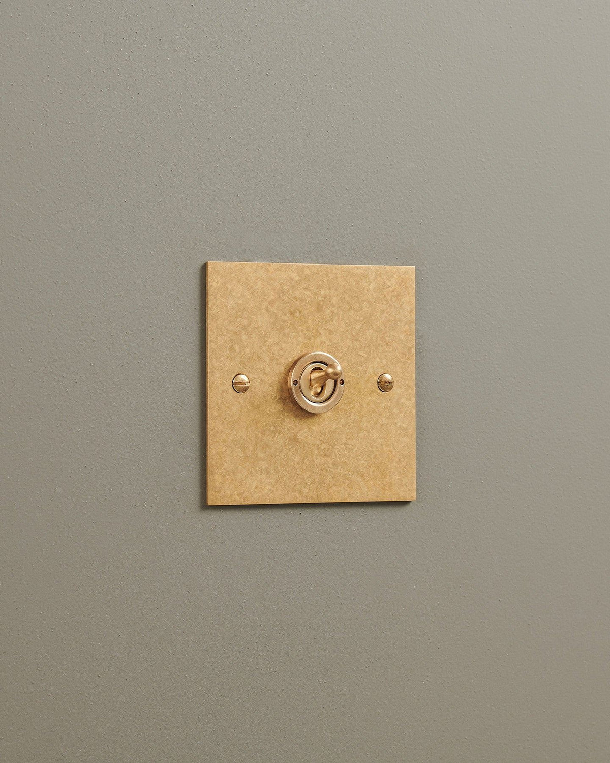 An oblique view of a 1 gang classic toggle switch in a mottled aged brass finish. TEST