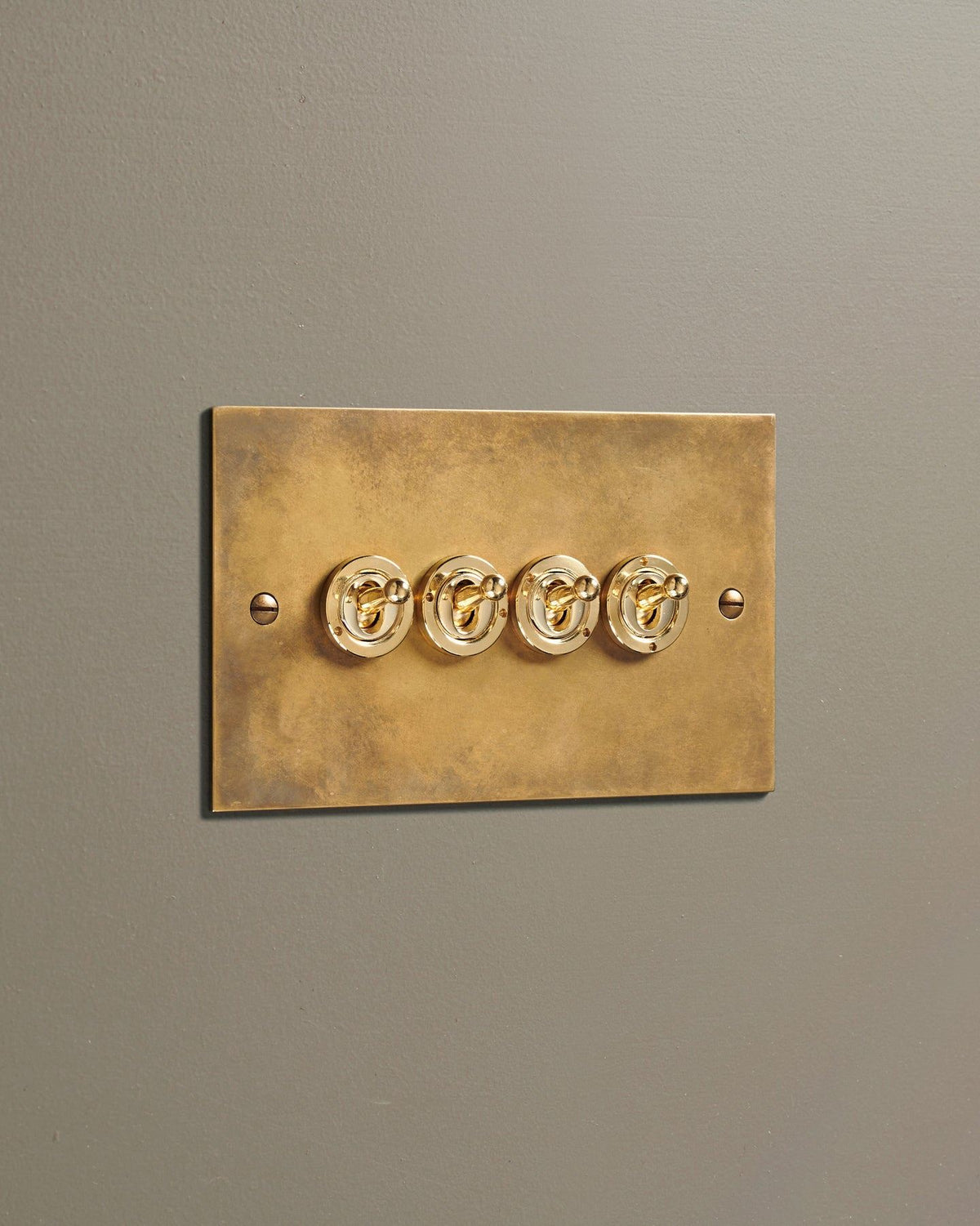 An oblique view of a 4 gang classic toggle switch in a warm burnished brass finish. TEST