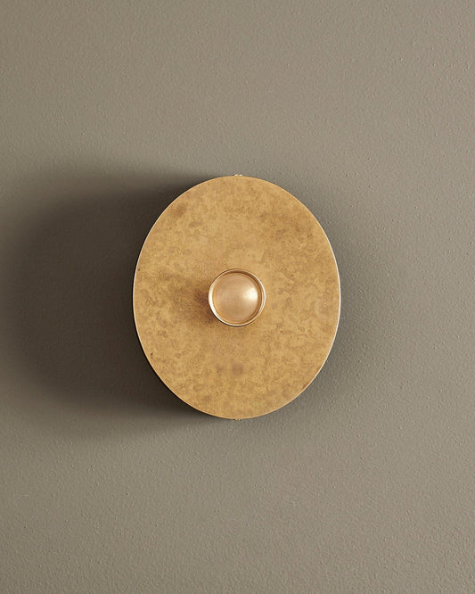 A straight-on view of a 1 gang oval-shaped dimmer switch in a mottled aged brass finish with a black base.