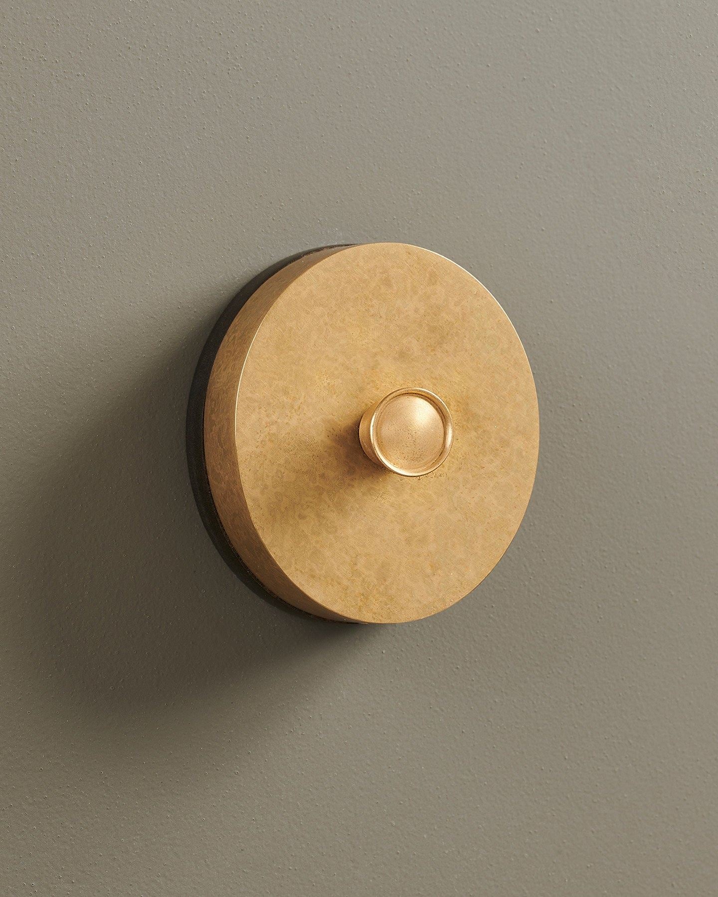 An oblique view of a 1 gang oval-shaped dimmer switch in a mottled aged brass finish with a black base.