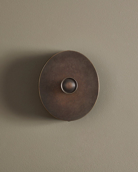 A straight-on view of a 1 gang oval-shaped dimmer switch in a dark oxidised brass finish with a black base.