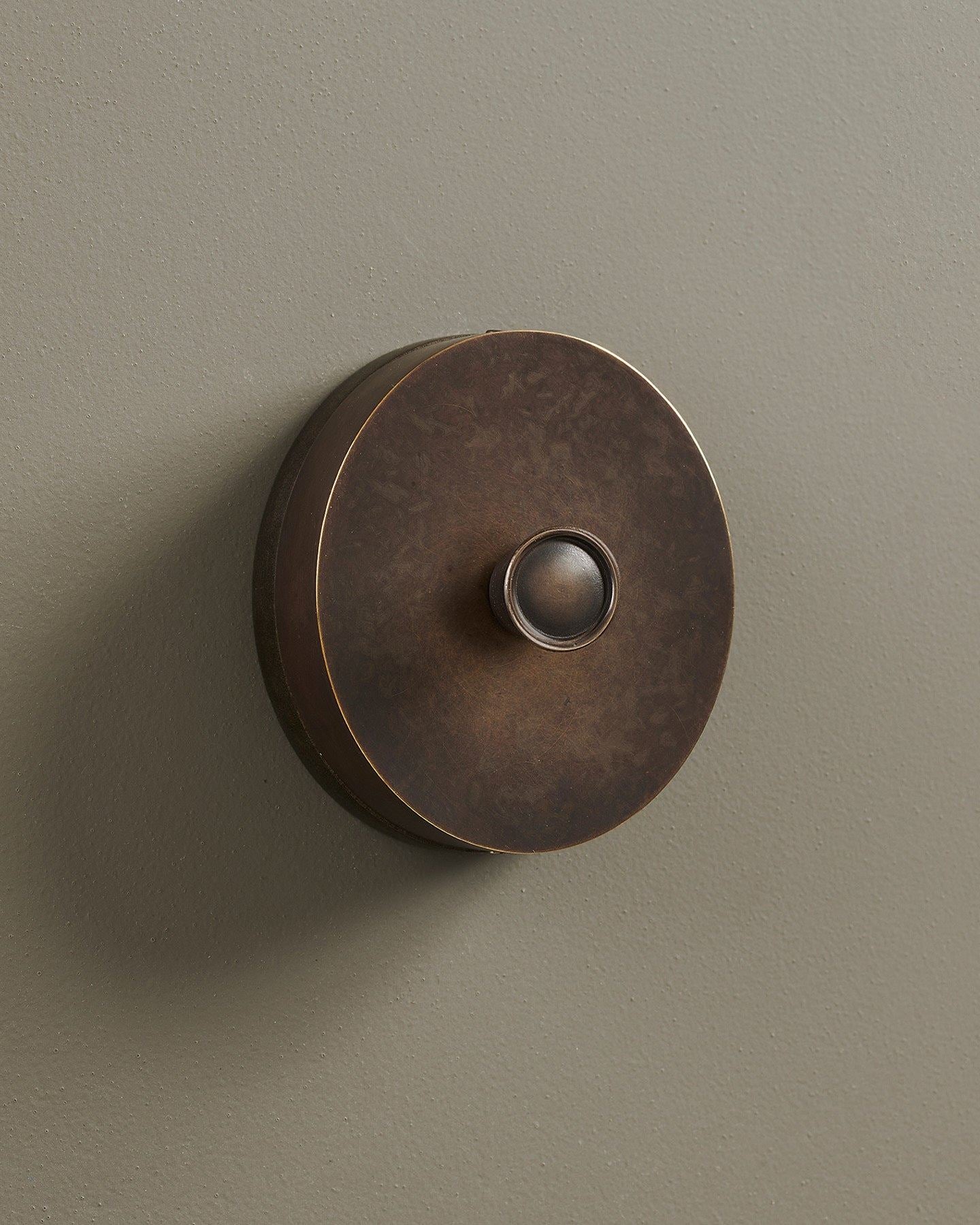 An oblique view of a 1 gang oval-shaped dimmer switch in a dark oxidised brass finish with a black base.