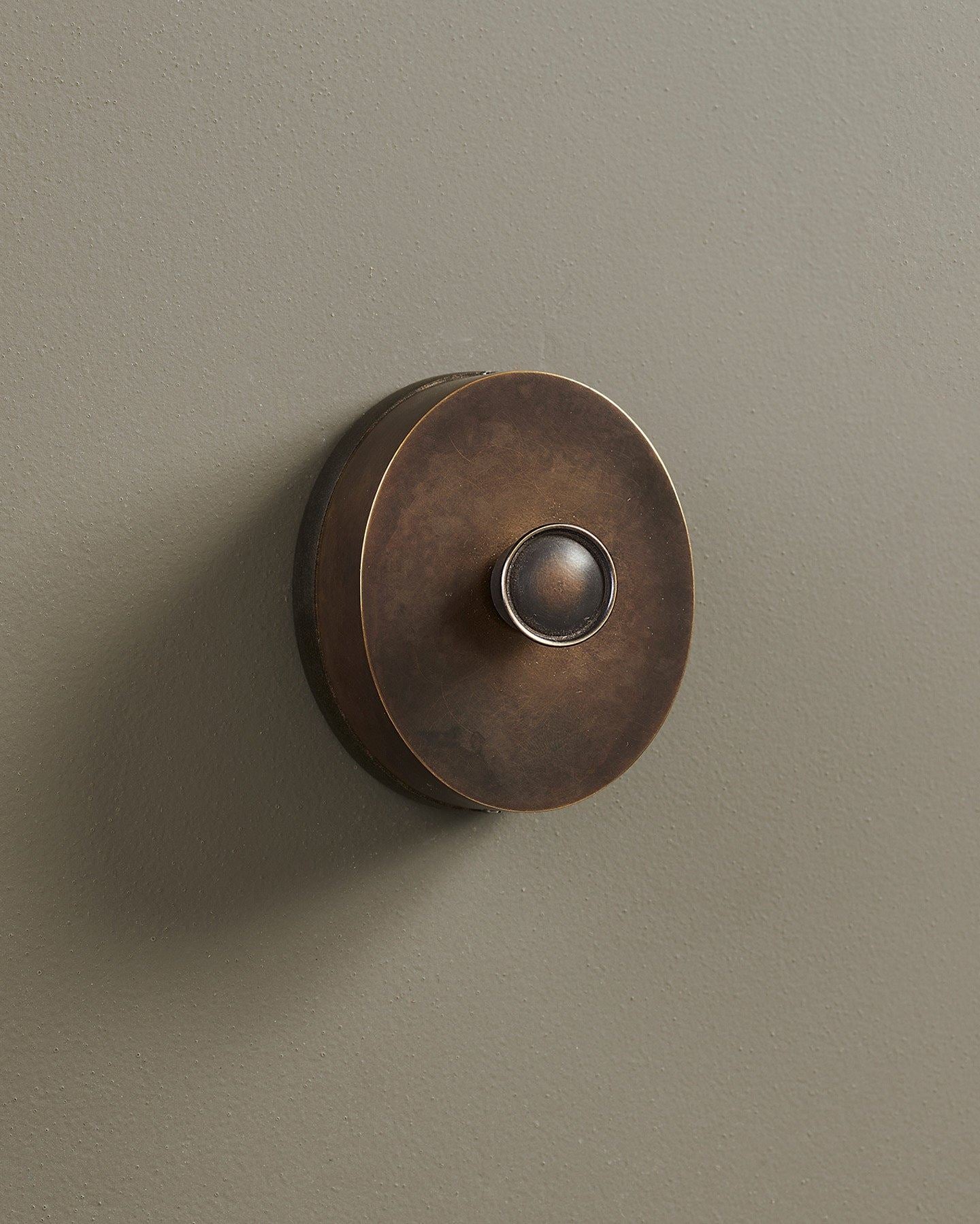 An oblique view of a small 1 gang oval-shaped dimmer switch in a dark oxidised brass finish with a black base.