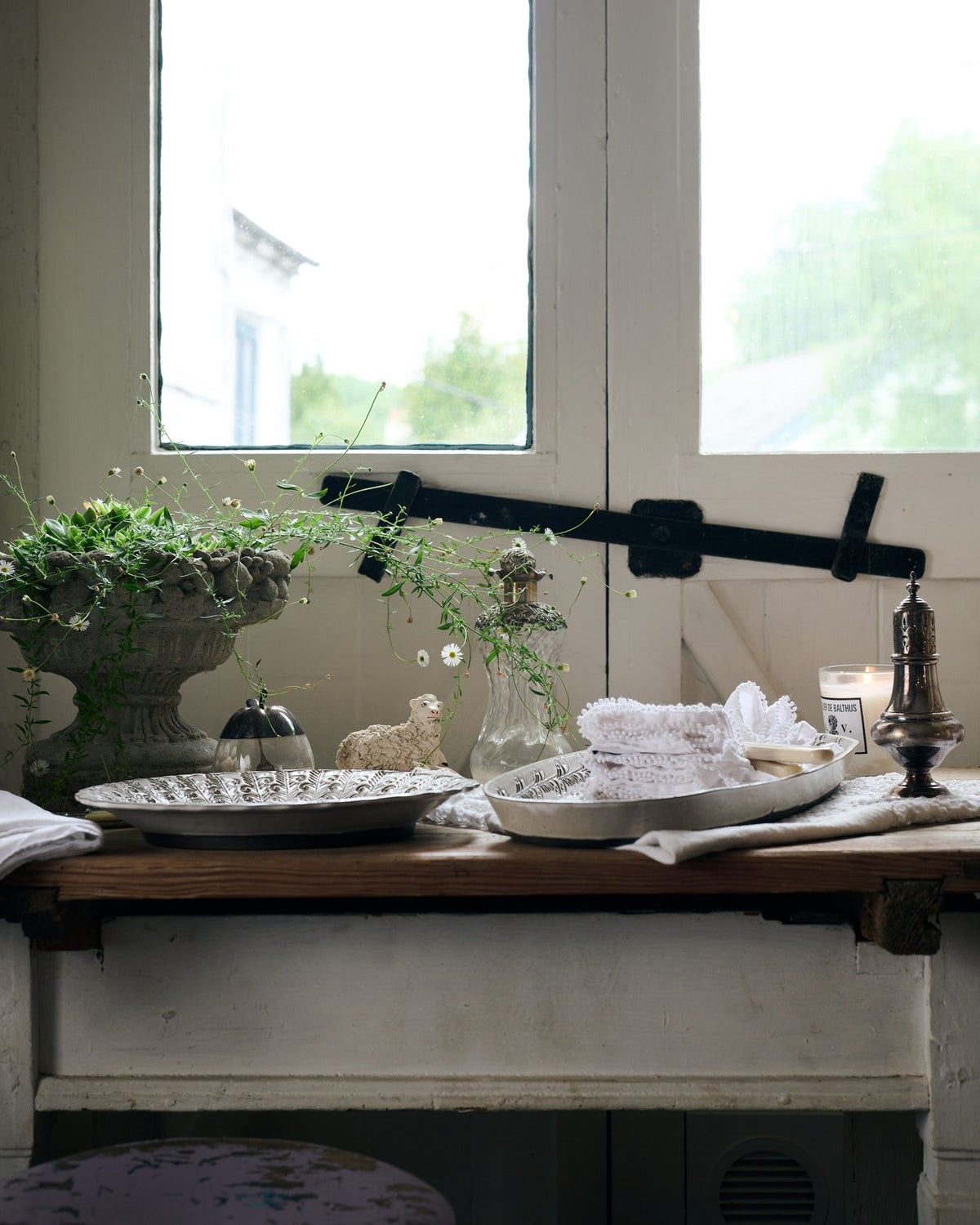 A profile view of two bohemian-style white ceramic platters on a vintage farmhouse table. TEST