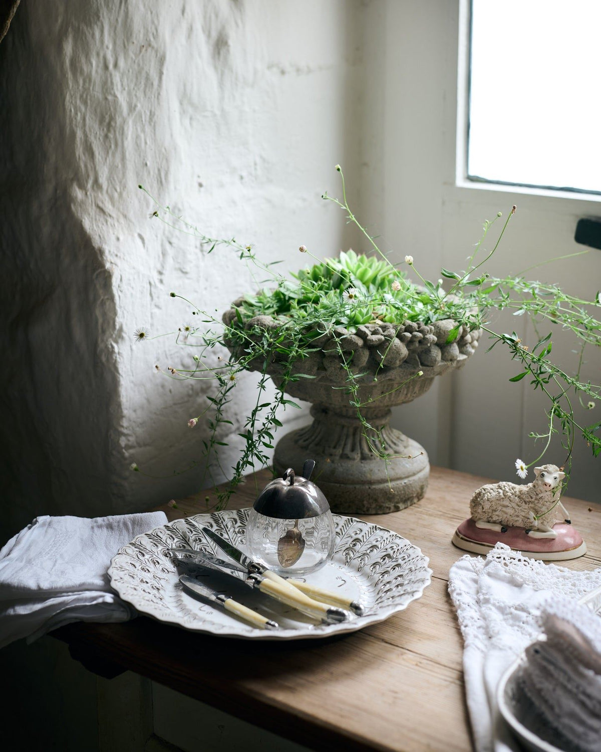 An oblique view of a round handmade bohemian-style white ceramic platter on a vintage farmhouse table. TEST