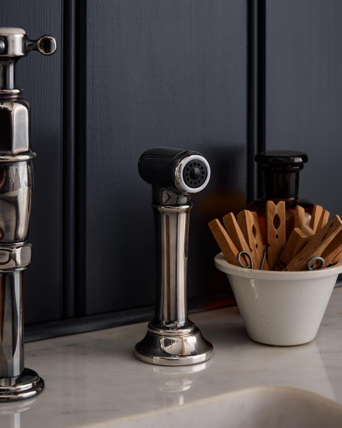 A close-up view of a traditional-style tarnished silver rinser tap.