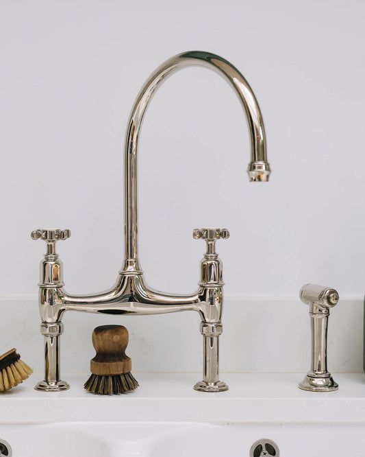 A close-up view of a traditional-style chrome mixer tap with crosshead handles and an independent rinser tap.
