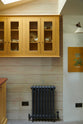 A quiet corner of the quaint and glamorous cottage kitchen, in shades of green and scullery yellow, includes a small sink run with an oak countertop and glazed wall cabinets. Lovingly decorated with vintage furniture, a floral painting, and deVOL mini creamware wall lights, the space exudes personality and charm while respecting the cottage's original textures.