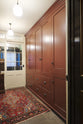 An oblique view of a practical Refectory red corridor with full-height cupboards and a large rug.
