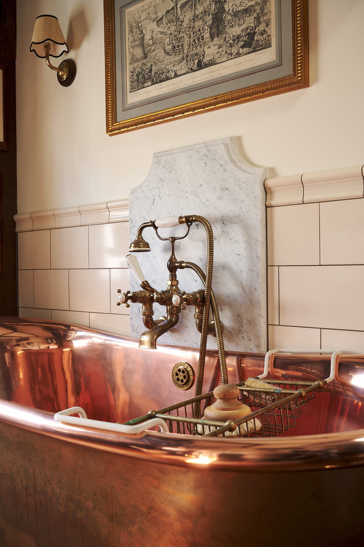 Behind a stunning copper bath, is a beautiful and practical cream subway splashback tiles.
