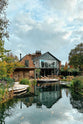 A stylishly remodelled Georgian house boasts a balcony, large French doors, and a spacious pond with fountains, surrounded by luscious fauna.