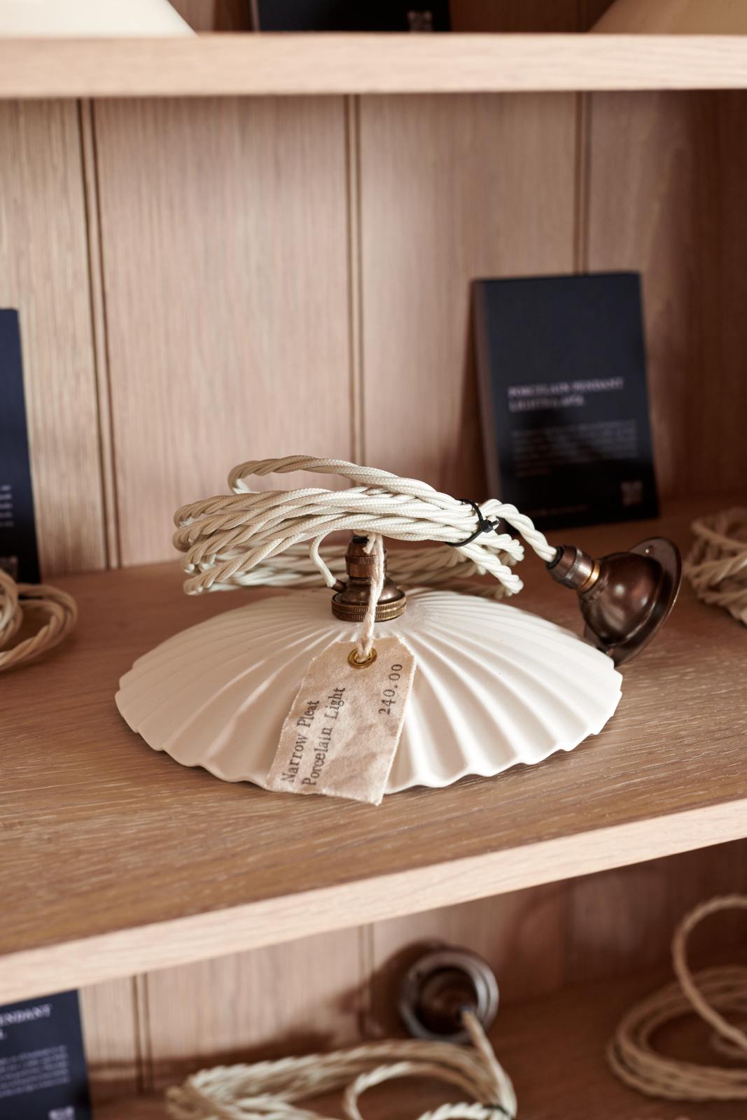 A closer look inside the glazed freestanding pantry cupboard reveals a narrow pleat porcelain light as part of the handsome range of oak furniture and lighting from the deVOL Haberdasher’s collection. Adorned with fabric tags and deVOL postcards, this space creates a beautiful homage to the English gentlemen’s haberdashery inspiration in a bricked wall showroom.