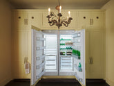 A simple corridor houses three sets of double cupboards; the middle cupboard is open to reveal an integrated fridge/freezer cupboard. Naturally decorated with a tea towel, chilled beverages of all kinds, and an antique chandelier, creating a clean and organised storage space.