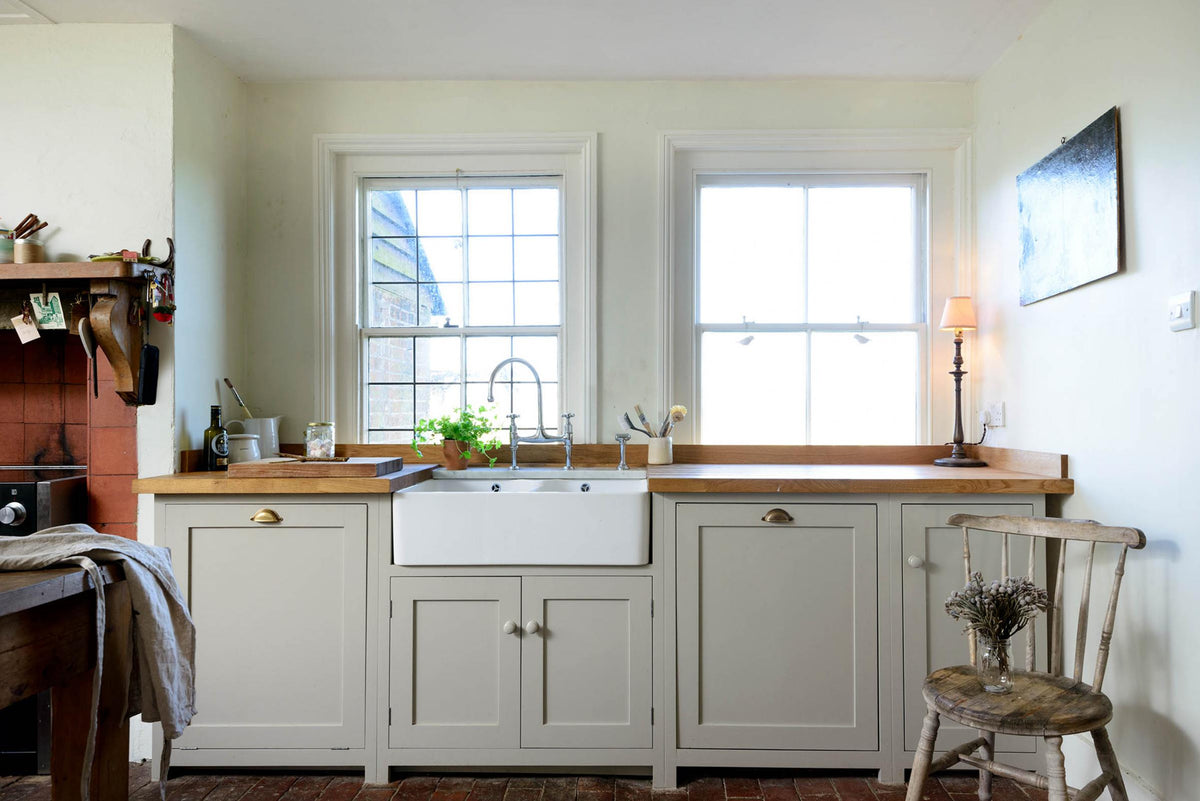 A closer look at the small and quaint mushroom-coloured Shaker kitchen’s features a sink run with a double Belfast sink, stave hardwood worktop, and an antique silver Ionian tap. Beautifully decorated with vintage furniture such as a large solid oak table, a silver scale, and assorted bric-a-brac, it creates a lovely social space full of character.