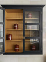 A closer look at a large Pantry Blue Shaker kitchen reveals wall cabinets with a Scullery Yellow interior and cream subway splashback tiles. Beautifully decorated with vintage ceramic containers bearing the names of dried ingredients, the kitchen presents a thoughtfully curated mix of collected pieces that fit together effortlessly.