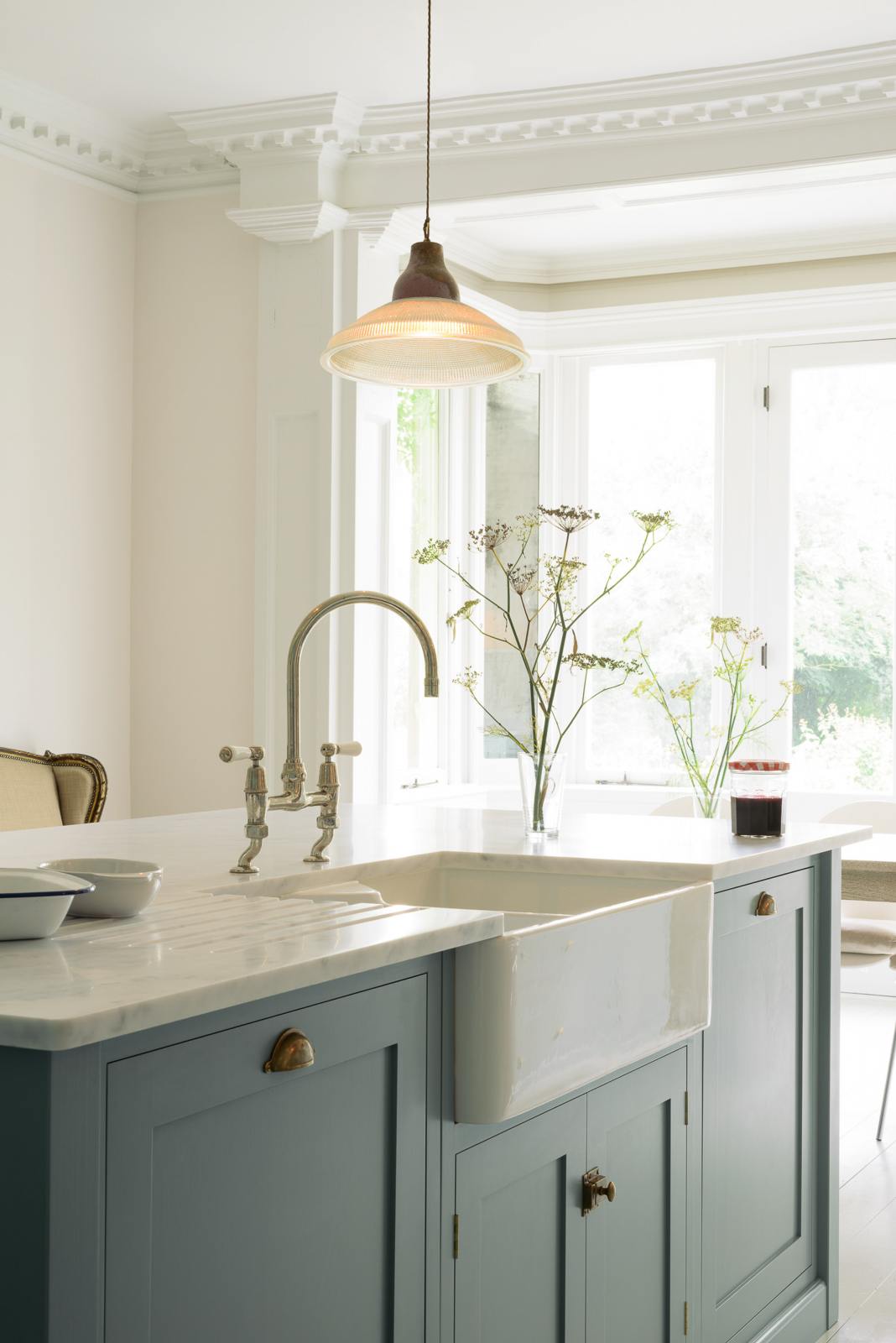A closer look at the double Belfast sink in the Trinity Blue kitchen island with a Carrara marble worktop. Natural light from the original French doors brightens the simple kitchen.