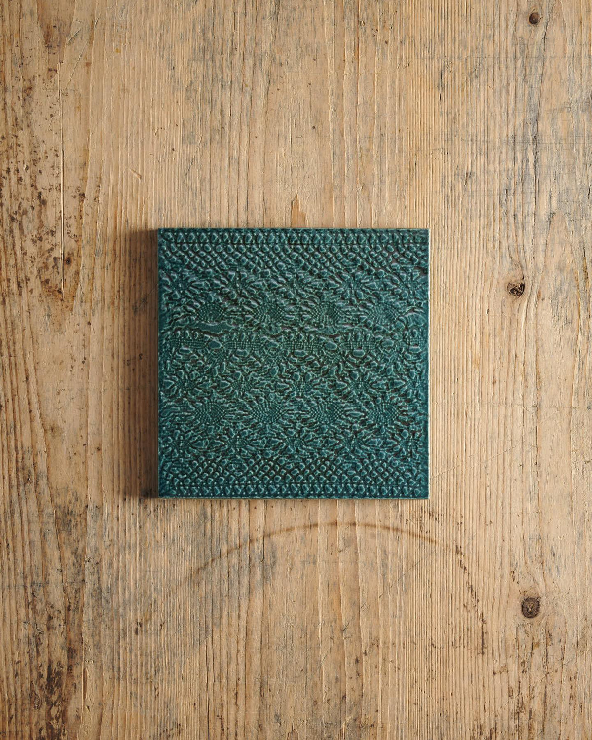Teal textured square on a wooden surface. | Venetian Square TEST
